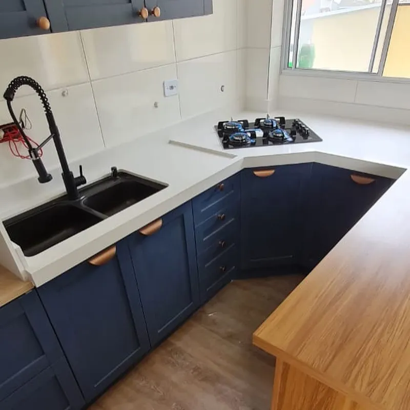 Cozinha em L com bancada clara e marcenaria azul