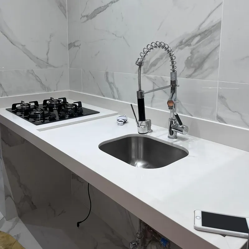 Bancada clara com cooktop e cuba de inox
