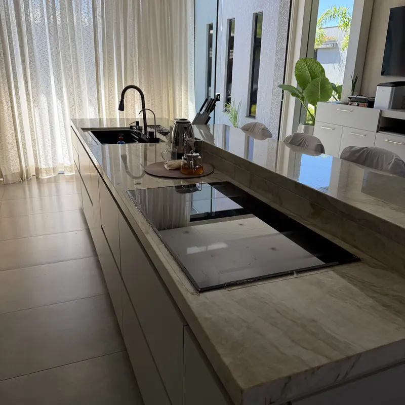 Ilha longa com cuba e cooktop em pedra clara