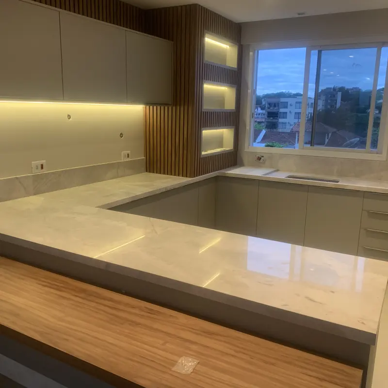 Cozinha em U com bancada clara e iluminação embutida
