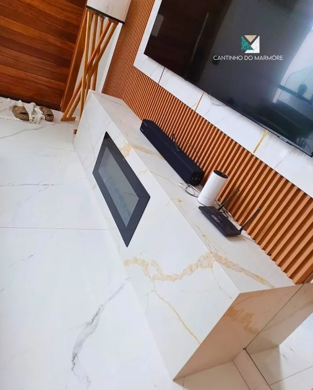 Painel e bancada em pedra clara na sala